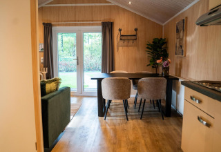 Bright dining area inside Lodge Deluxe at Holiday park Latour in the Netherlands, with four chairs and garden view.