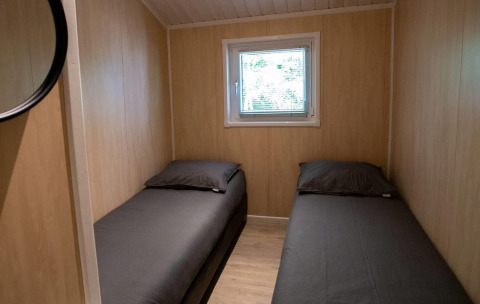 Stanza con due letti singoli e pareti in legno nella Lodge Deluxe al Holiday park Latour, Paesi Bassi.