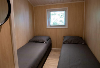Room with two single beds and wooden walls at Lodge Deluxe in Holiday park Latour, the Netherlands.
