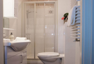 Modern bathroom with shower, toilet, sink, and towel radiator at Lodge Deluxe, Holiday park Latour, Netherlands.
