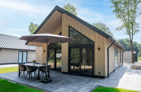 Modern Ecovilla Boszicht Luxe lodge, featuring outdoor dining set and umbrella on a spacious tiled patio.