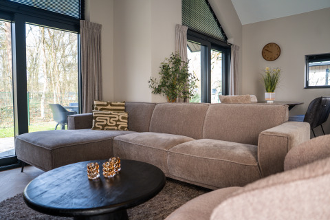 Soggiorno moderno in Ecovilla Boszicht Luxe, Holiday park Latour, Paesi Bassi, con divano accogliente.