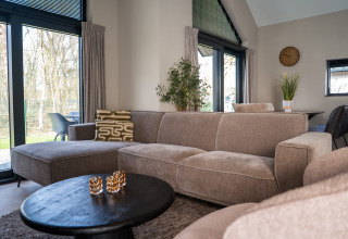 Soggiorno moderno in Ecovilla Boszicht Luxe, Holiday park Latour, Paesi Bassi, con divano accogliente.