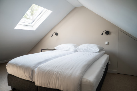 Bedroom with double bed, skylight, and a modern minimalist design in Ecovilla Boszicht Luxe, Latour, Netherlands.
