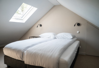 Dormitorio con cama doble, tragaluz y diseño minimalista moderno en Ecovilla Boszicht Luxe, Latour, Países Bajos.