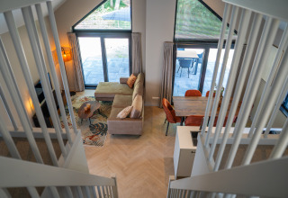 Vista dalle scale su soggiorno e sala da pranzo di Ecovilla Waterzicht Luxe presso Holiday park Latour, Paesi Bassi.