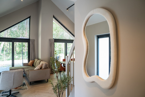 Modern lounge of Ecovilla Waterzicht Luxe at Holiday park Latour, Netherlands, with large windows and decor.
