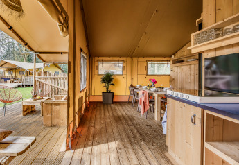 Innenansicht des Safari-Zelts De Bos Tent in Gooise Heide, Niederlande, mit Ess- und Wohnbereich.