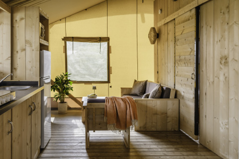 Interno accogliente della tenda safari De Heide Tent con dettagli in legno a Gooise Heide, Paesi Bassi.