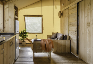 Interno accogliente della tenda safari De Heide Tent con dettagli in legno a Gooise Heide, Paesi Bassi.