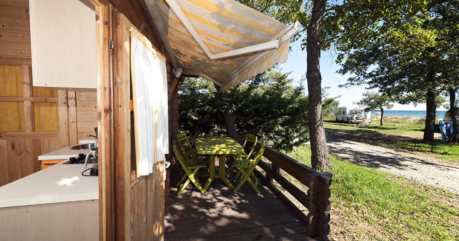 Houten terras van Chalet Marina op Camping Merendella, Frankrijk, met tuinset en uitzicht op zee.
