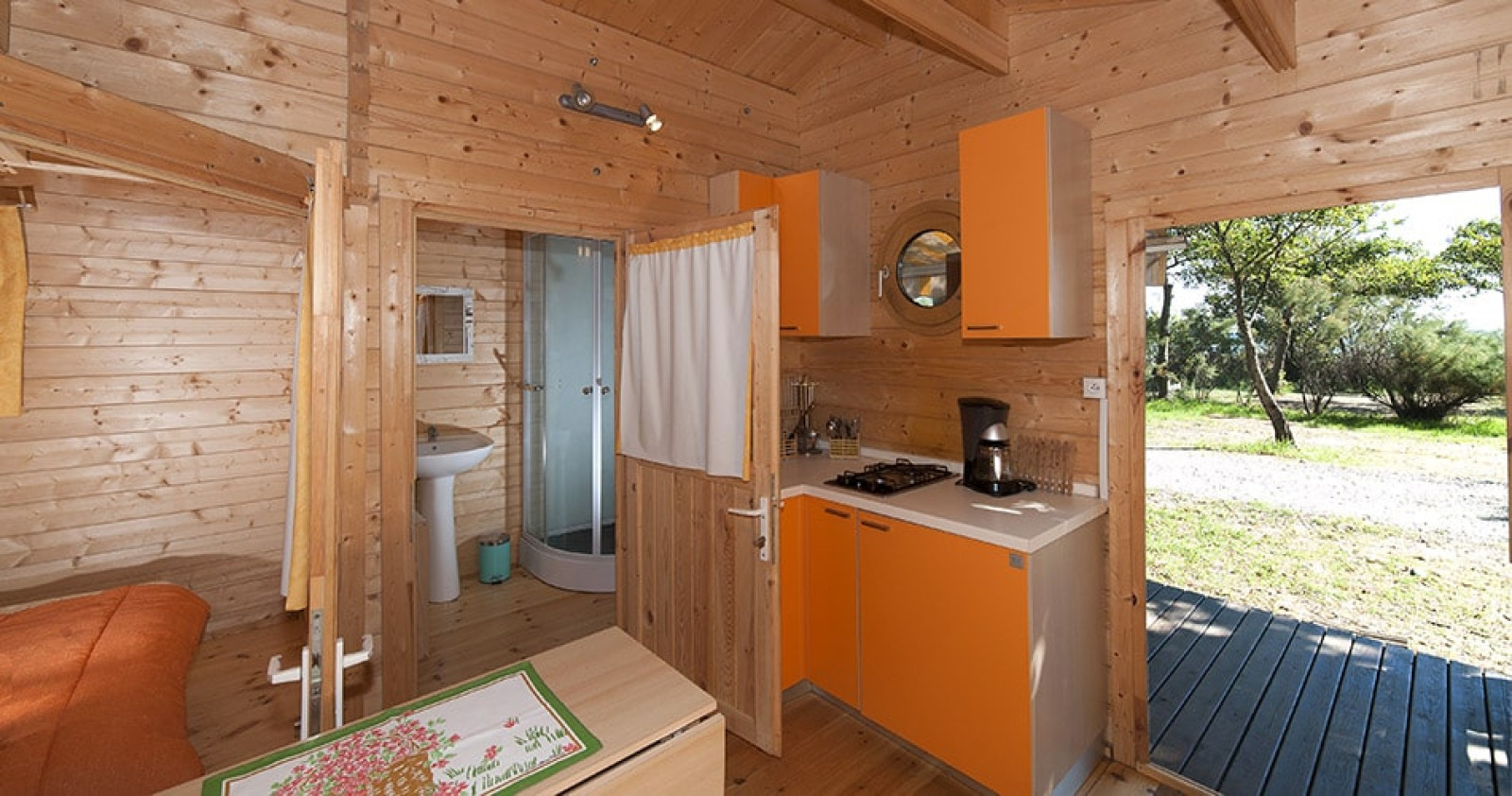 Interieur van Chalet Marina bij Camping Merendella met kleine keuken, badkamer en houten inrichting.
