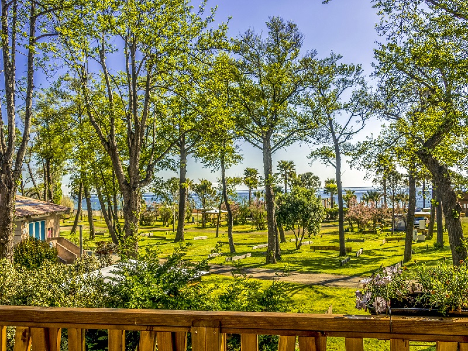Uitzicht vanaf Lodge Prestige op palen met zeezicht bij Camping Merendella in Frankrijk, tussen groene bomen.