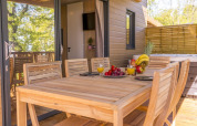 Essbereich im Freien der Lodge Prestige auf Stelzen mit Meerblick im Camping Merendella, Frankreich.