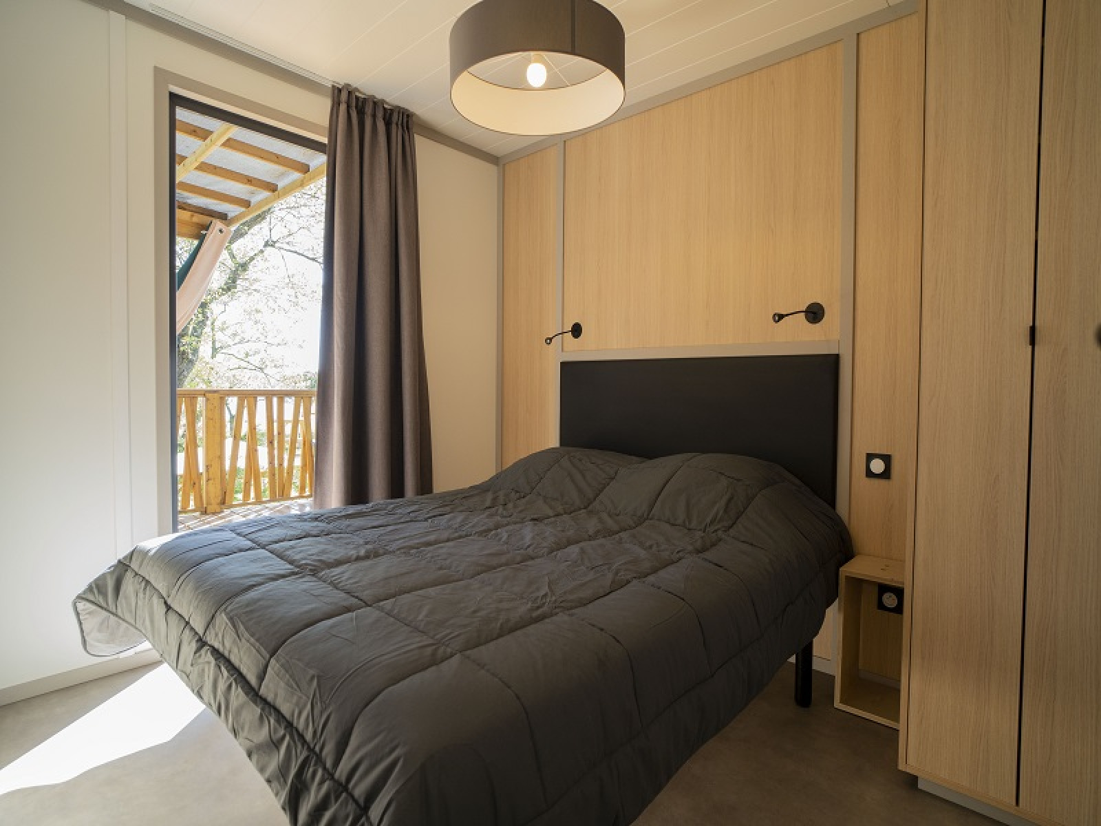 Slaapkamer in Lodge Prestige op palen met zeezicht bij Camping Merendella in Frankrijk, modern ingericht.