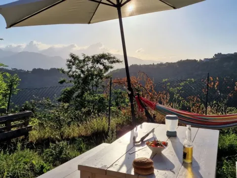 Sonnige Aussicht von Safaritent premium plek auf Camping Pian d'Amora, Italien, mit Essen und Hängematte.