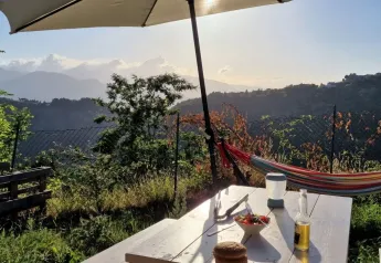 Zonnig uitzicht vanuit Safaritent premium plek op Camping Pian d'Amora, Italië, met eten en hangmat.