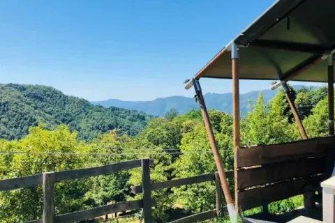 Uitzicht vanaf Safaritent premium plek op Camping Pian d'Amora in Italië, met groene bergen op de achtergrond.