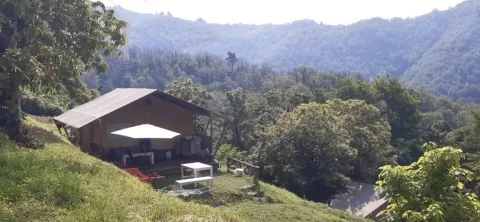 Safariteltet på nederste terrasse af Camping Pian d'Amora med skovklædte bjerge i Italien i baggrunden.