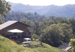 Safaritent op het onderste terras van Camping Pian d'Amora, omzoomd door groene heuvels in Italië.