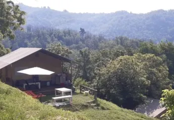 Safarizelt auf der unteren Terrasse des Campingplatzes Pian d'Amora mit bewaldeten Hügeln in Italien.
