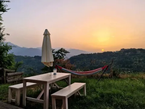 Zonsondergang met hangmat, picknicktafel en parasol bij Safaritent premium plek, Camping Pian d'Amora, Italië.