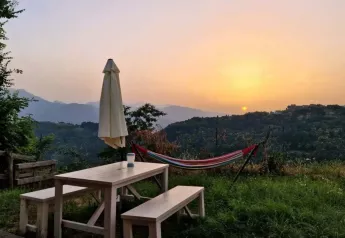 Sonnenuntergang mit Hängematte, Picknicktisch und Sonnenschirm am Safaritent premium plek, Camping Pian d'Amora in Italien.