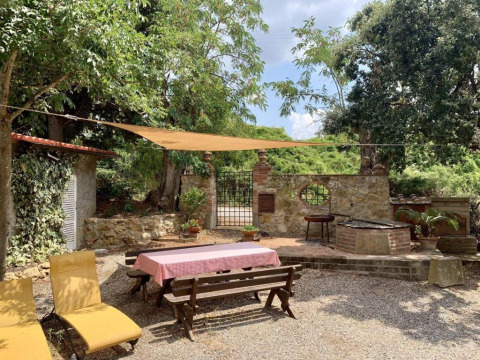 Buitenruimte met tafel, banken, ligstoelen en zonnescherm bij Agricampeggio La Prugnola in Toscane.