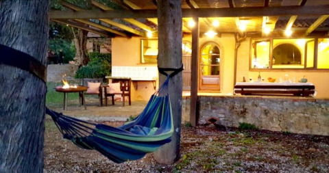 Buitenhoek van Agricampeggio La Prugnola in Toscane met hangmat en gezellig verlichte veranda.