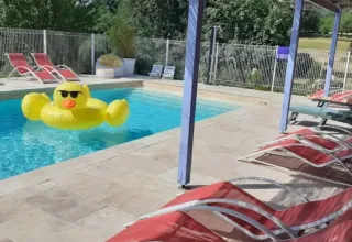 Udendørs poolområde i Domaine de La Velle, Occitanie, Frankrig med røde liggestole og stor badeand.