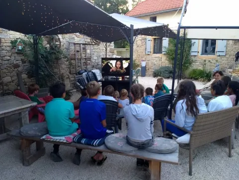 Kinderen en volwassenen kijken samen buiten een film bij Domaine de La Velle vakantiepark in Occitanië, Frankrijk.