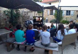 Børn og voksne ser film under åben himmel i Domaine de La Velle, et feriepark i Occitanie, Frankrig.