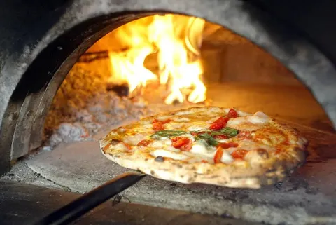 En lækker pizza bliver bagt i en autentisk stenovn med flammer, et højdepunkt på Domaine de La Velle.