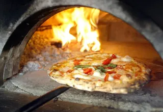 En lækker pizza bliver bagt i en autentisk stenovn med flammer, et højdepunkt på Domaine de La Velle.