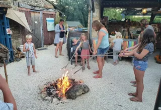 Gezinnen en kinderen roosteren marshmallows bij een kampvuur op Domaine de La Velle in Occitanië, Frankrijk.