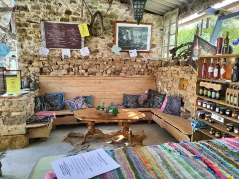 Hyggelig lounge med stenvæg, træbænke, puder og lokale produkter hos Domaine de La Velle i Occitanie.