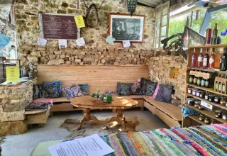 Hyggelig lounge med stenvæg, træbænke, puder og lokale produkter hos Domaine de La Velle i Occitanie.