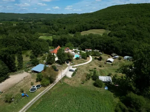 Luftfoto af Domaine de La Velle, en feriepark i Occitanie, Frankrig, omgivet af skov og grønne bakker.