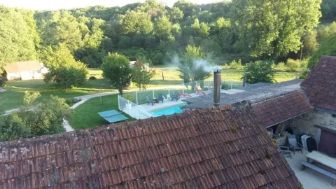 Udsigt over Domaine de La Velle i Occitanie med swimmingpool, terracotta-tag og frodig grøn natur.
