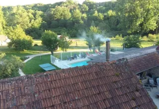 Udsigt over Domaine de La Velle i Occitanie med swimmingpool, terracotta-tag og frodig grøn natur.