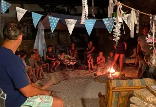 Mensen rond een kampvuur bij Domaine de La Velle vakantiepark in Occitanië, Frankrijk.