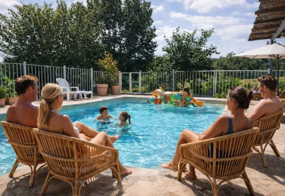 Gezinnen ontspannen bij het zwembad van Domaine de La Velle vakantiepark in Occitanië, Frankrijk op een zonnige dag.