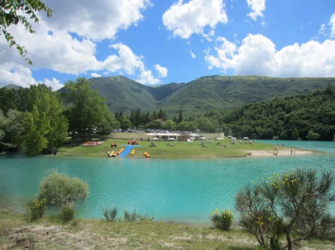 Scenic blue lake with grassy shore and green mountains near Montelparo in the Marche region, Italy.