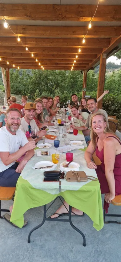 Groep mensen dineert samen buiten onder een verlichte pergola bij Agricampeggio Tasteria in Marche, Italië.