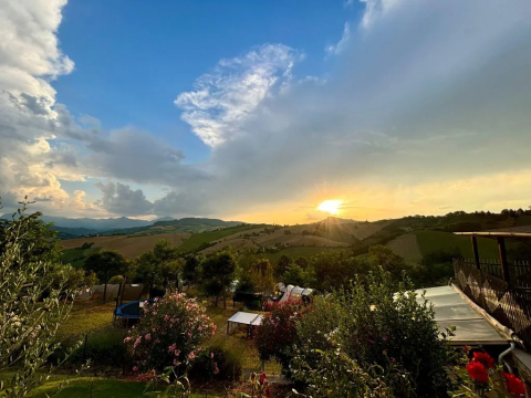 Zonsondergang boven de heuvels bij Agricampeggio Tasteria, een vakantiepark in Marche, Italië, met bloemen.