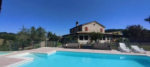 Maison en pierre avec piscine et transats sous ciel bleu à l’Agricampeggio Tasteria, Marches, Italie.