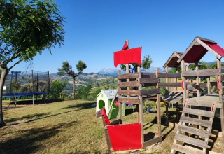 Parco giochi e trampolino ad Agricampeggio Tasteria nelle Marche, Italia, con vista sulle montagne.