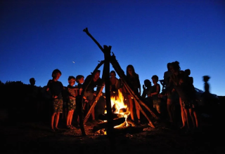 Des enfants autour d’un feu de camp au crépuscule à Agricampeggio Tasteria, parc de vacances dans les Marches, Italie.