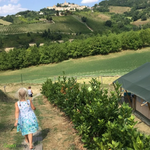 Twee kinderen lopen over een pad bij Agricampeggio Tasteria vakantiepark in Marche, Italië, tussen groene heuvels.