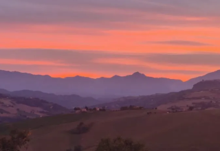 Zonsondergang boven heuvels en bergen bij Agricampeggio Tasteria, Marche, Italië, met kleurrijke lucht.
